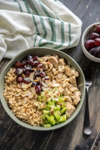 A bowl of chicken salad and brown rice with grapes and celery