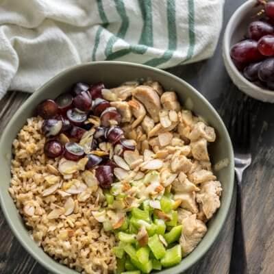 A bowl of chicken salad and brown rice with grapes and celery