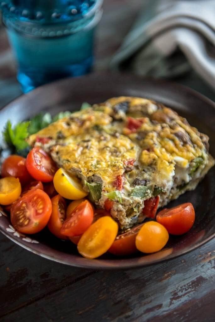 Healthy Breakfast Casserole with vegetables on a black plate with tomatoes