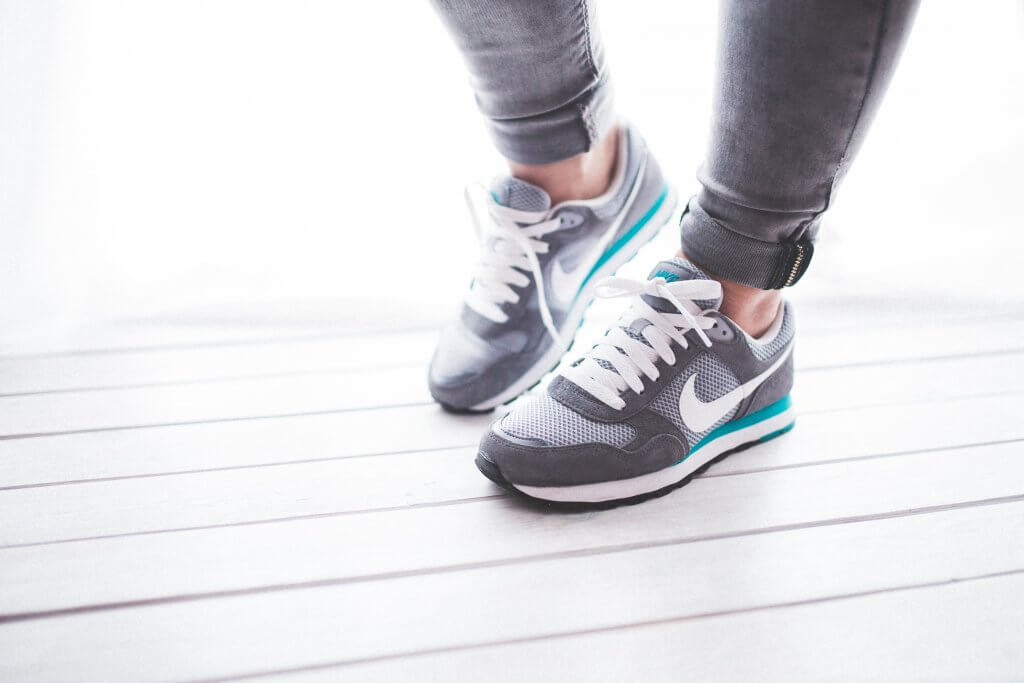 A woman in shoes on a white floor before starting her workout routine