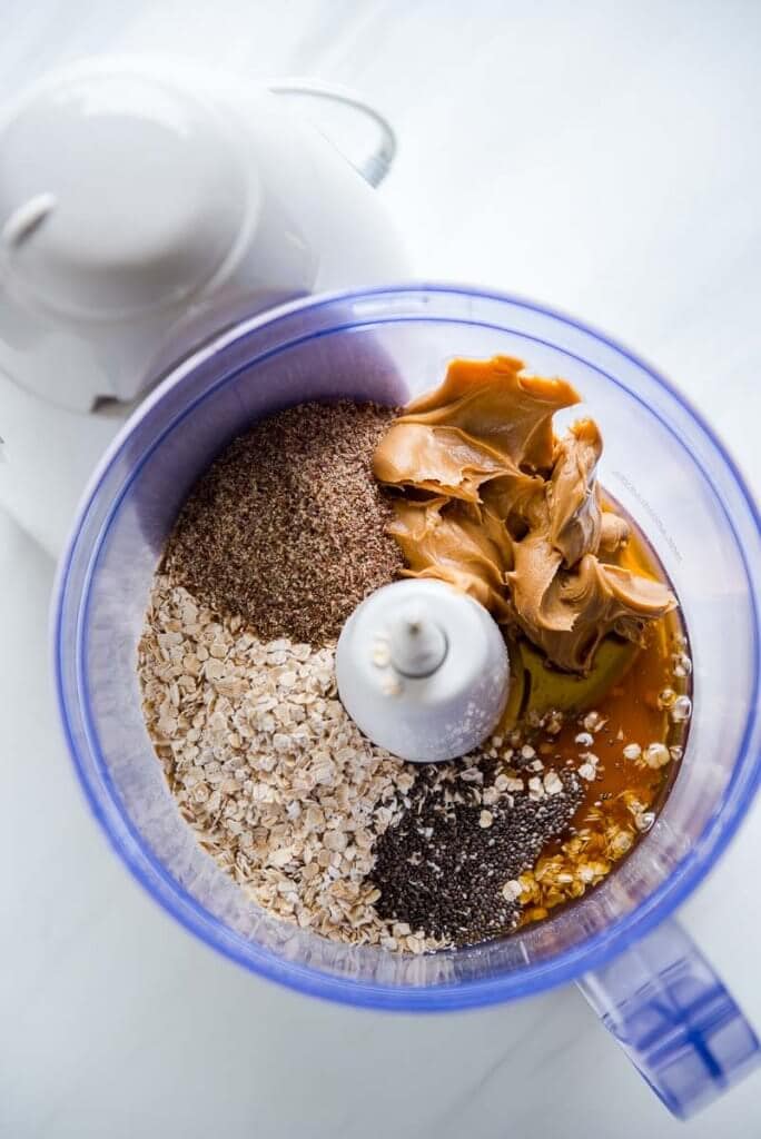 Overhead view of a food processor with oats, flax, chia, honey and pb