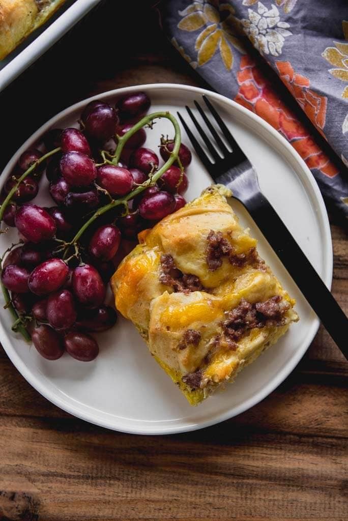 Breakfast Casserole with biscuits on a white plate with grapes
