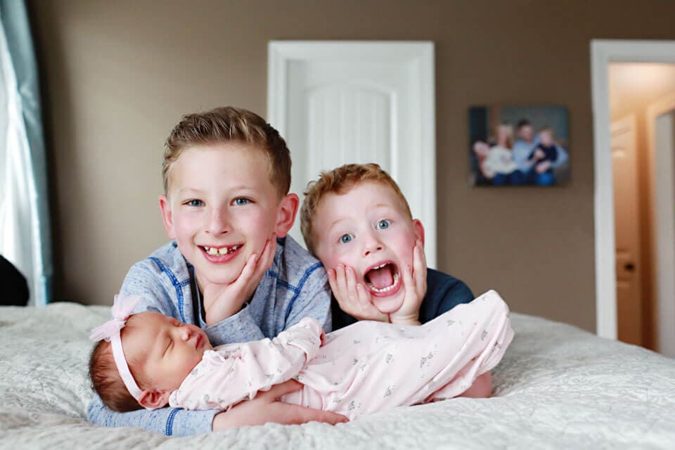 Two brothers holding their new baby girl