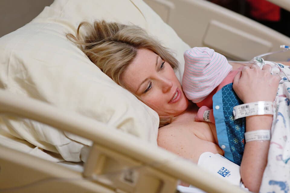 A woman holding her newborn baby in a hospital bed
