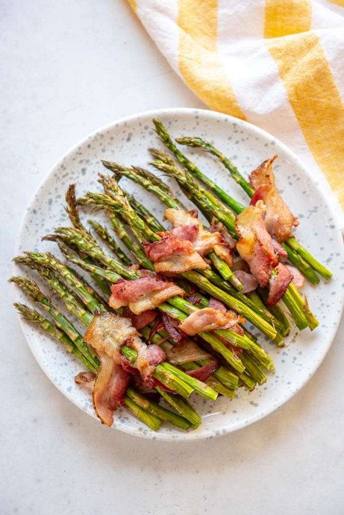 Asparagus wrapped in bacon on a white plate