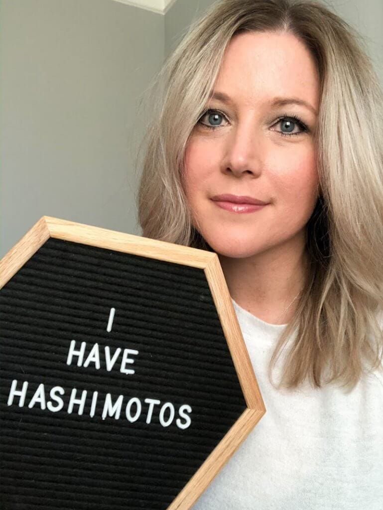 a woman holding a sign that says I have hashimoto's