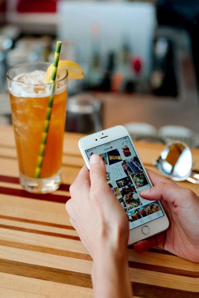 A woman holding a phone with an iced tea in the background