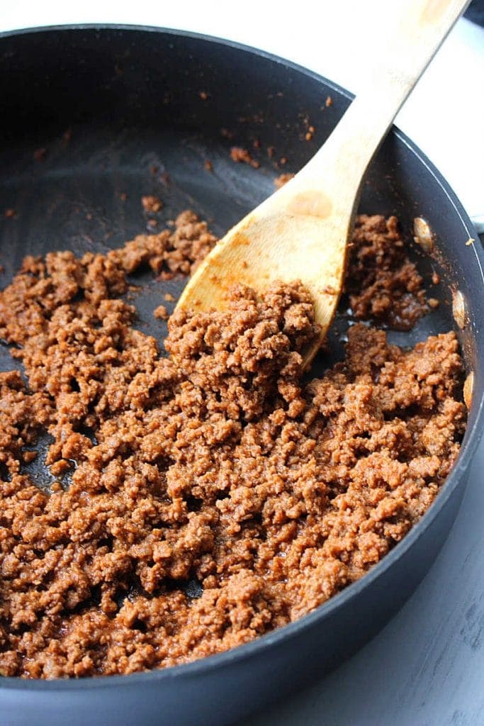 Homemade sloppy joes in a skillet with a wooden spoon