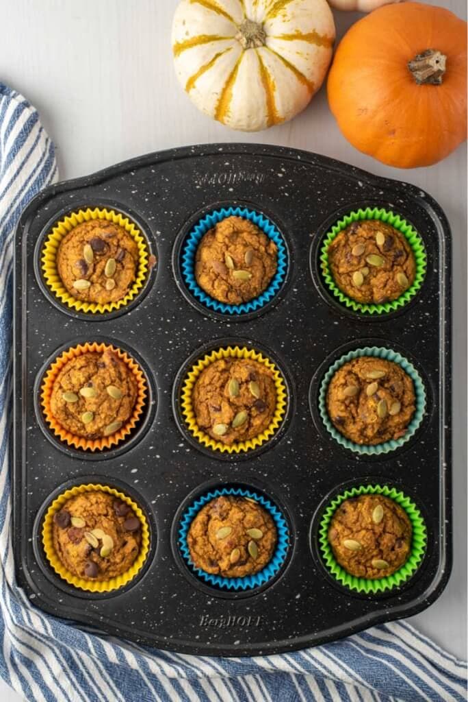 a muffin tin with baked healthy pumpkin muffins in them