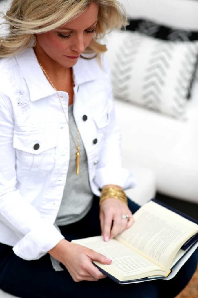 Woman in a white jacket reading a book