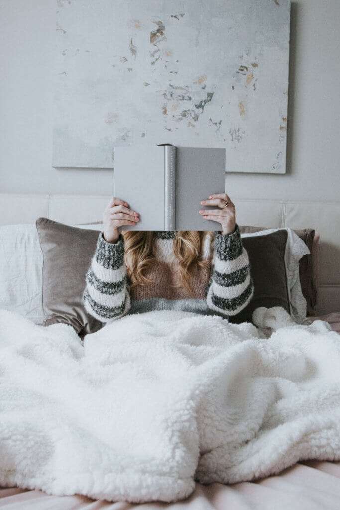 A girl reading a book in bed