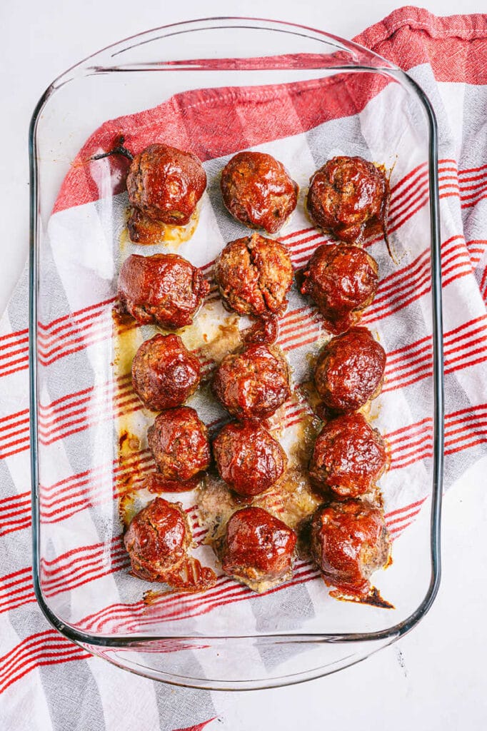 baking dish full of bbq meatballs with red and white napkin underneath the pan