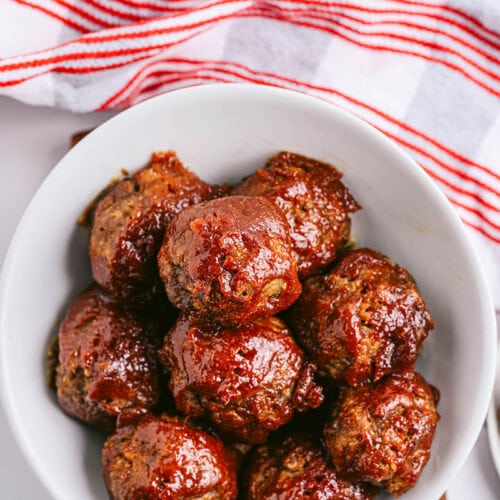 a bowl of bbq meatballs in a white bowl and with a red and white napkin