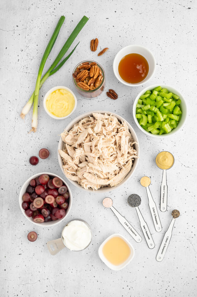 all of the ingredients for california chicken salad including chicken, grapes, green onions, celery, pecans, honey, spices 