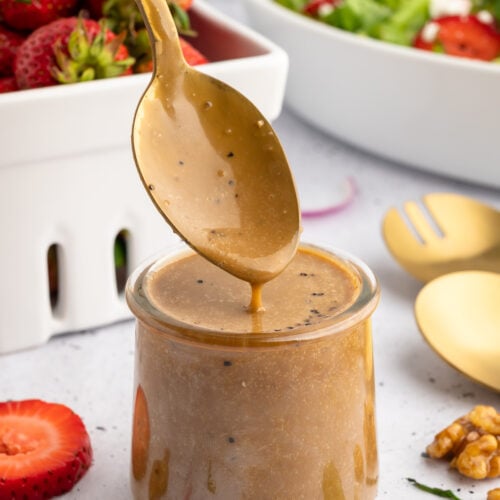 a glass jar filled with creamy balsamic dressing with a spoon coming out of it