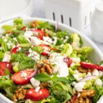 Up close picture of strawberry goat cheese salad with a bowl of strawberries behind the bowl