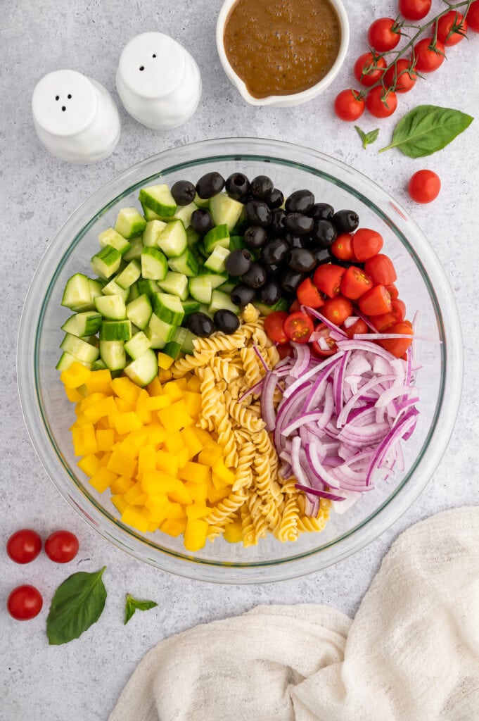 a bowl filled with all the ingredients for balsamic pasta salad before it is stirred